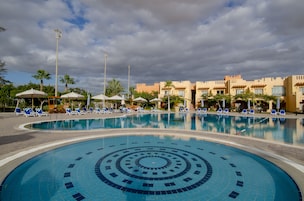 Una piscina al aire libre, sombrillas, sillones reclinables de piscina