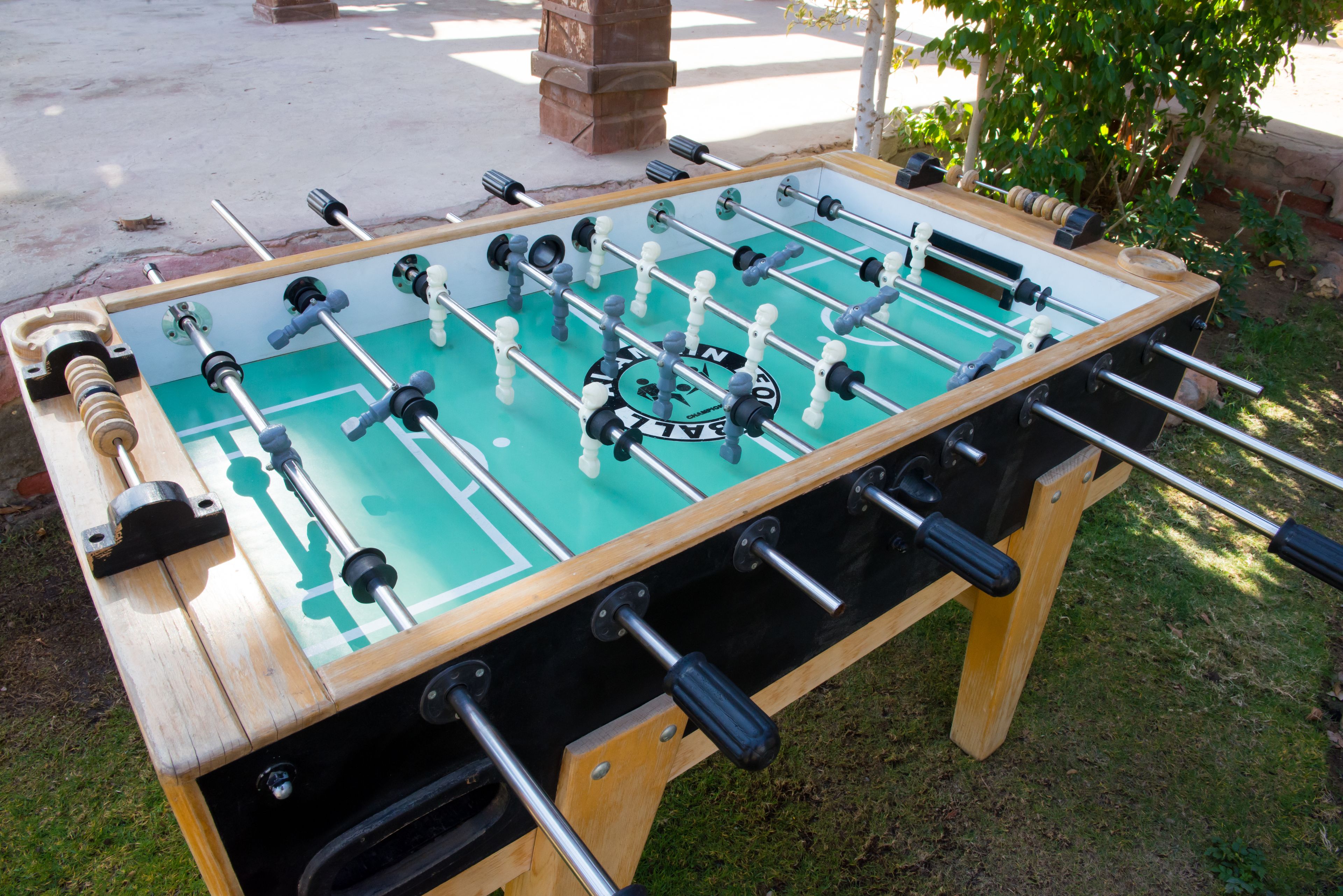 A foosball table with a wooden frame and a green playing surface.