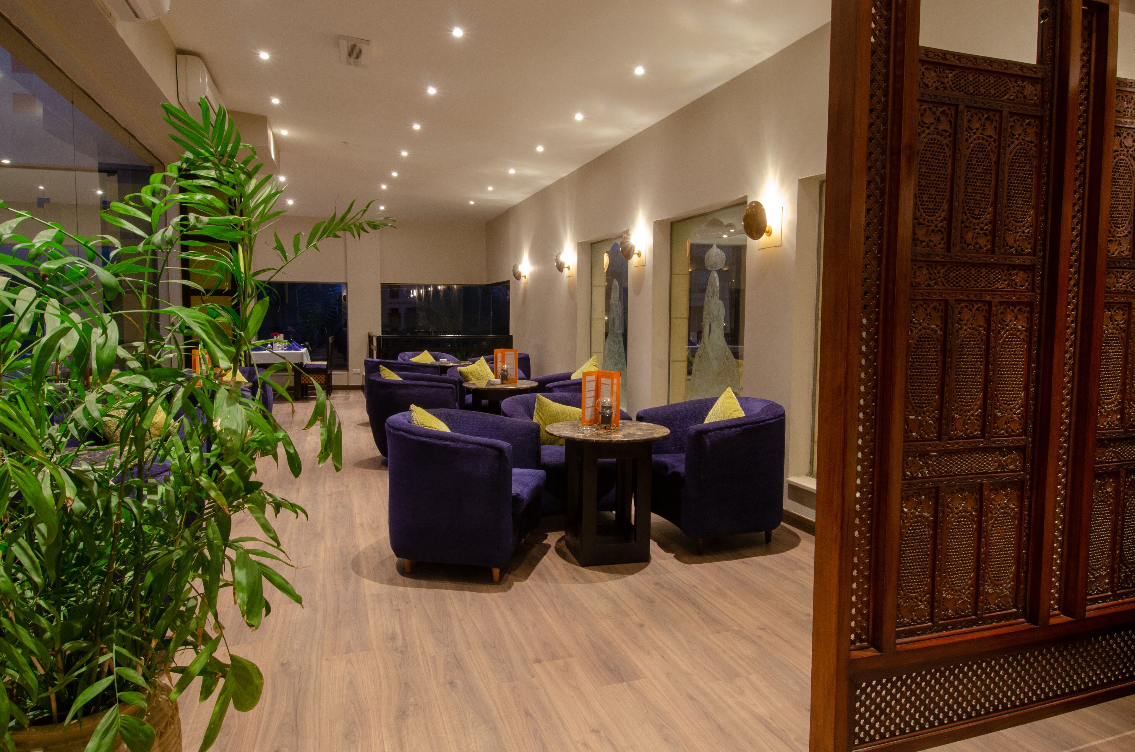 A modern lounge area with purple sofas, a round table, and a large wooden door.
