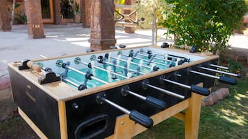 A wooden foosball table with black and white balls, set outdoors on a grassy area.