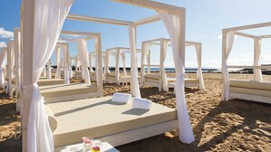 Un resort frente al mar con camas con dosel blanco y vista despejada al océano.