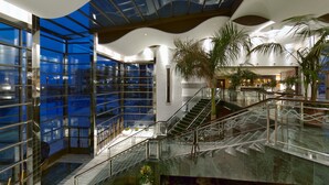 Un interior moderno con un atrio de vidrio, una escalera y plantas de interior.