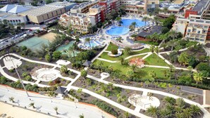 Un resort con varias piscinas, cancha de tenis y jardines ajardinados.