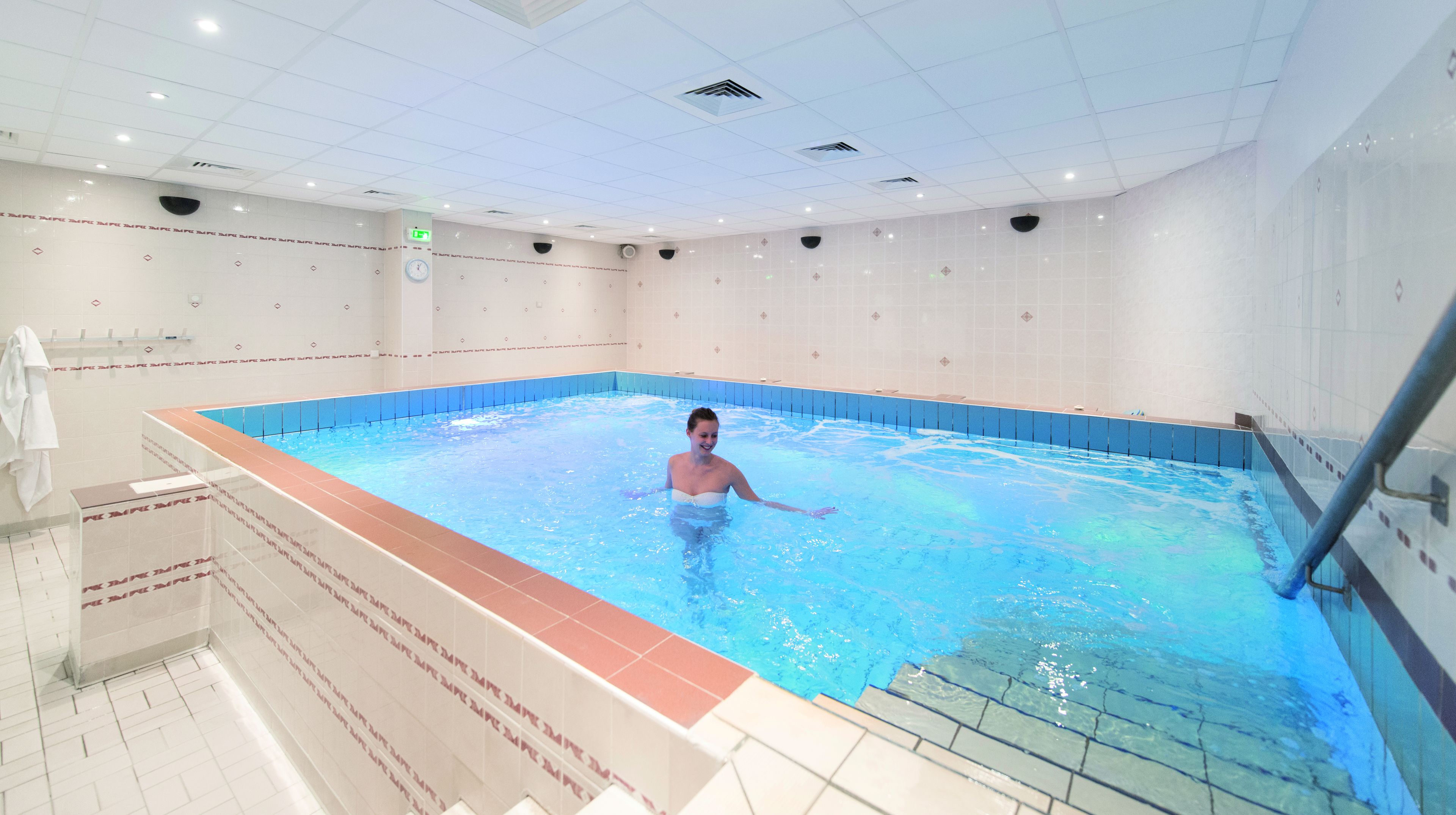 Una persona en una piscina con paredes de azulejos e iluminación empotrada en el techo.