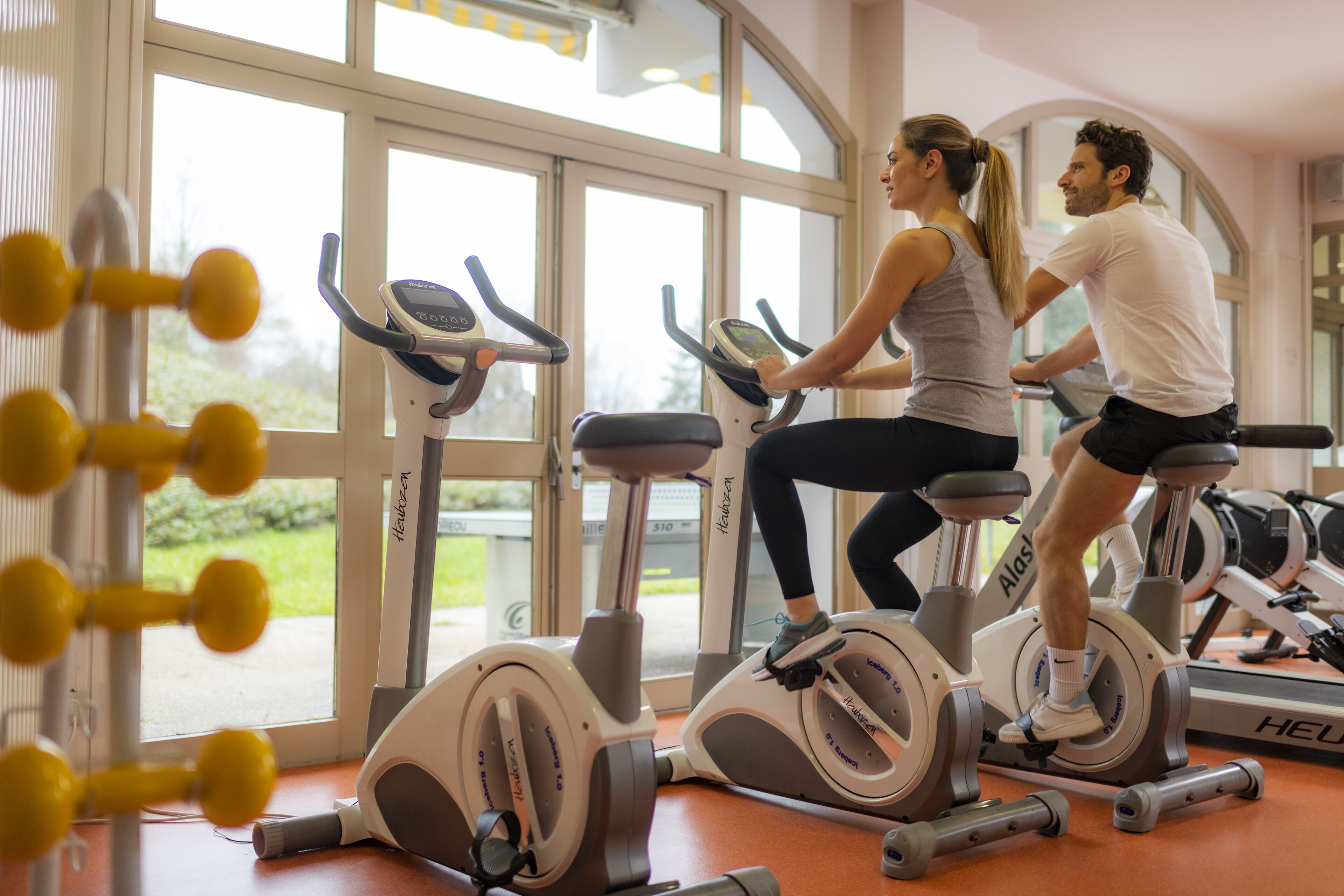 A gym with stationary bikes and a large window.