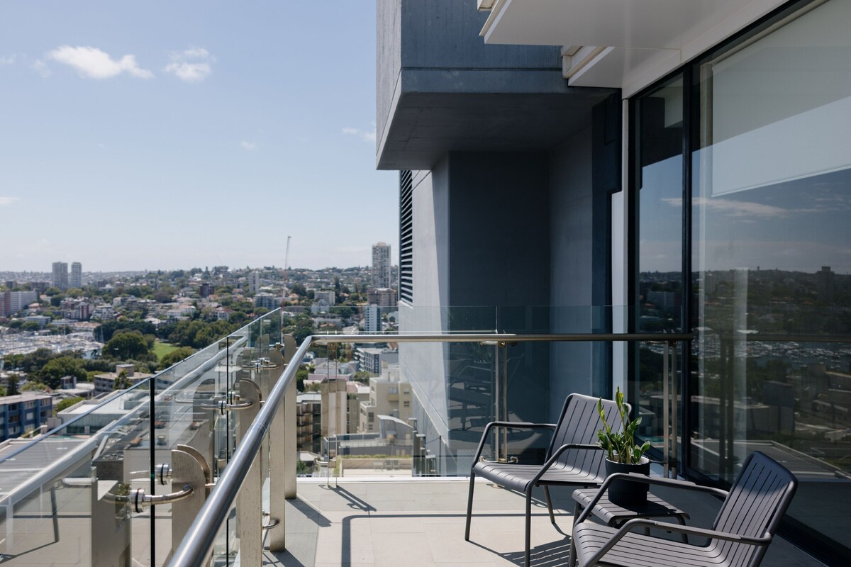 A balcony with a glass railing overlooking a cityscape.