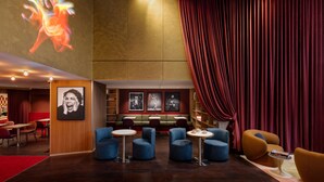 Un moderno hall con una cortina roja, zona de estar y obras de arte en las paredes.
