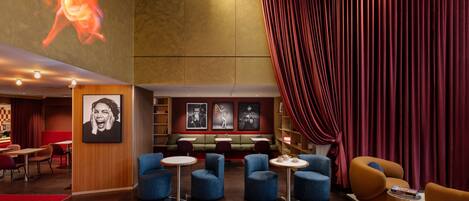 A modern lobby with a red curtain, seating area, and artwork on the walls.