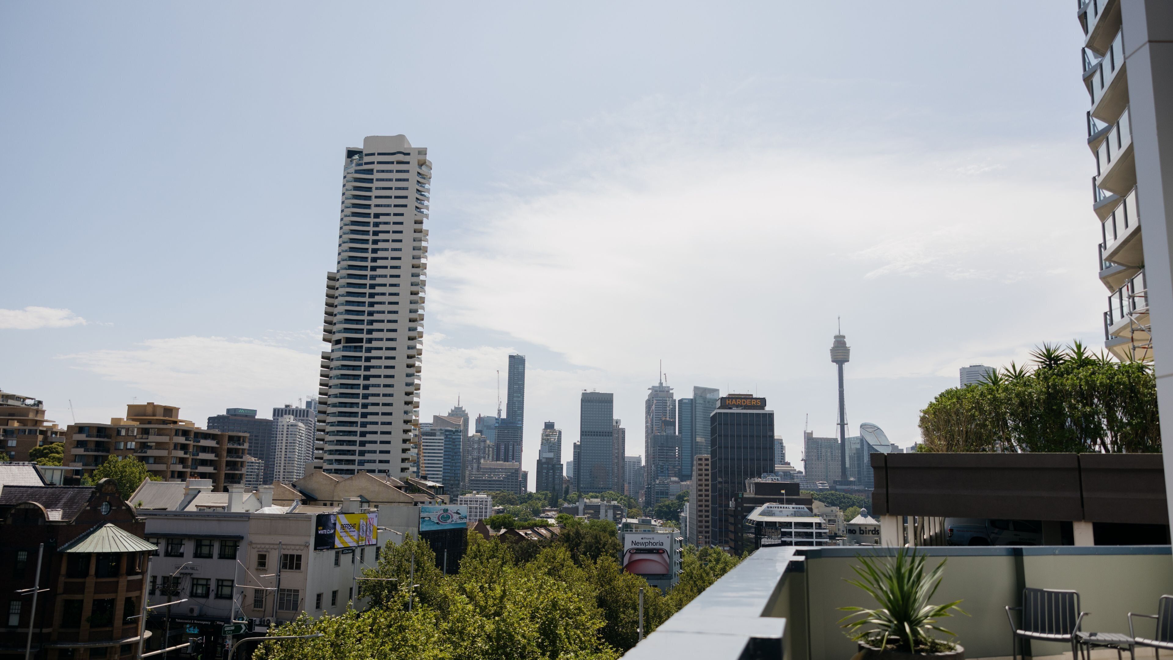 A high-rise building with a modern design, surrounded by other tall buildings and a clear sky.