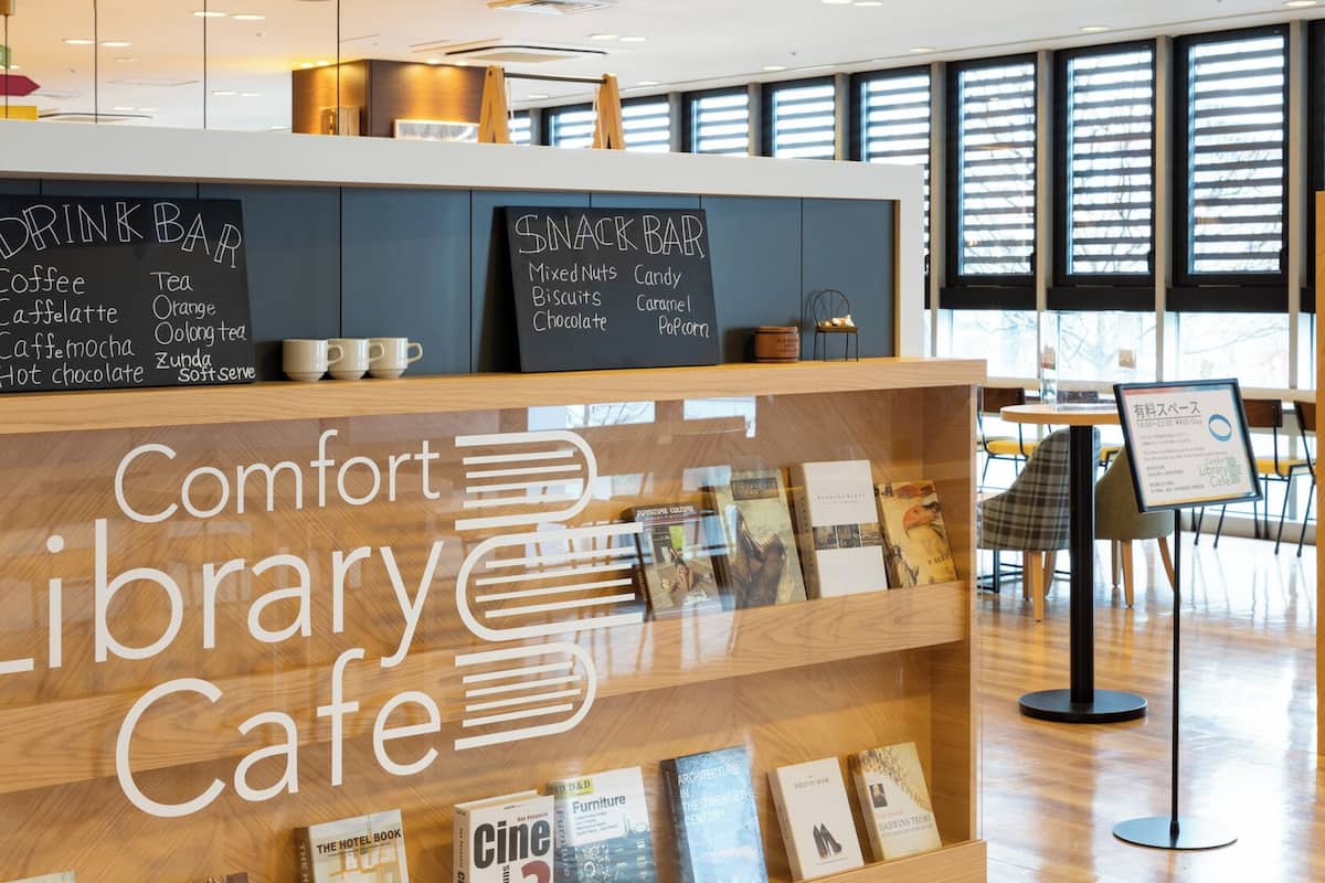 A library cafe with a drink bar, bookshelves, and a seating area.