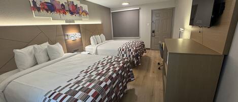 A hotel room with two beds, a TV mounted on the wall, a desk, and a painting of a city skyline.