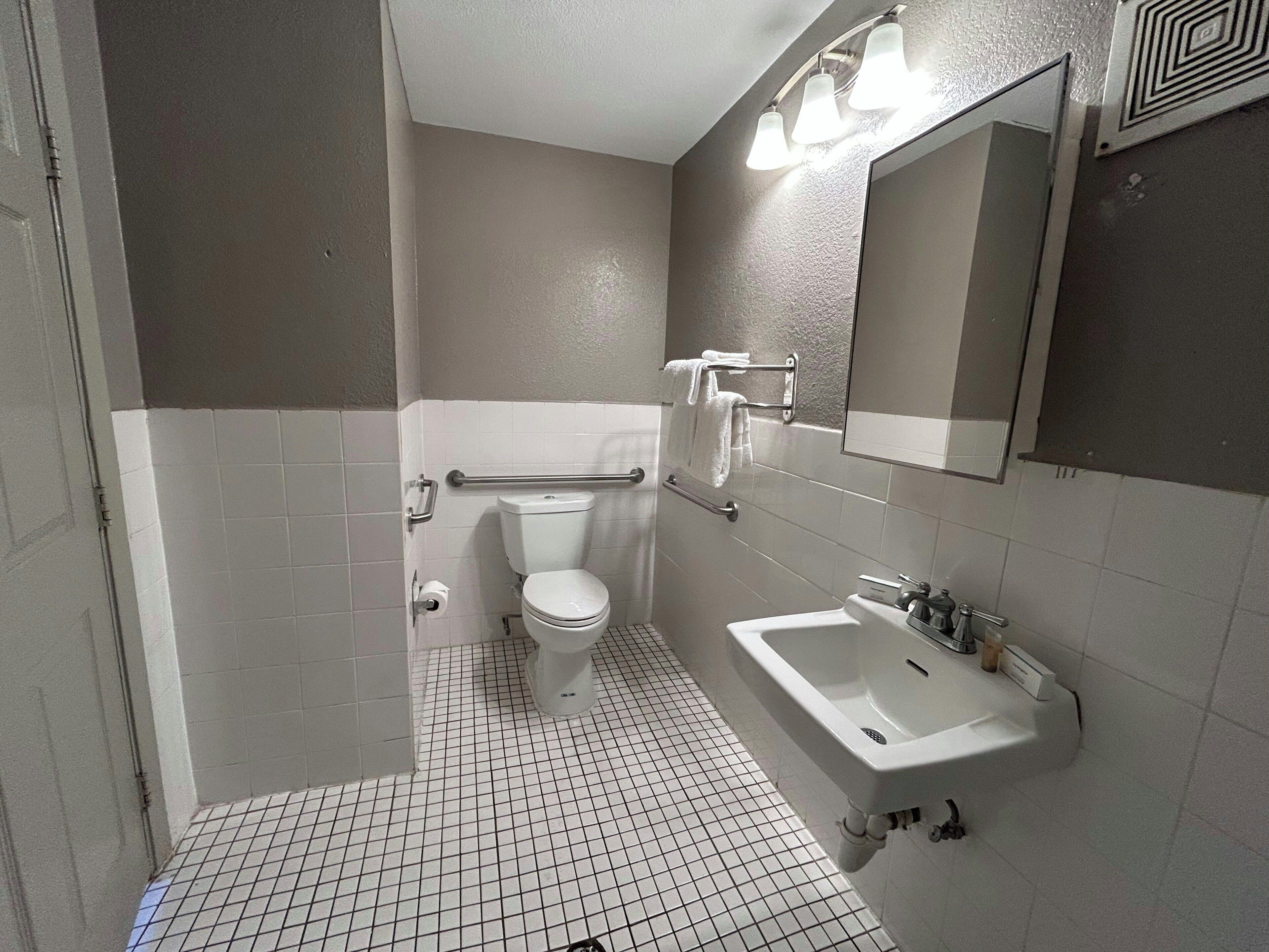 A small, compact bathroom with a toilet, sink, and mirror.