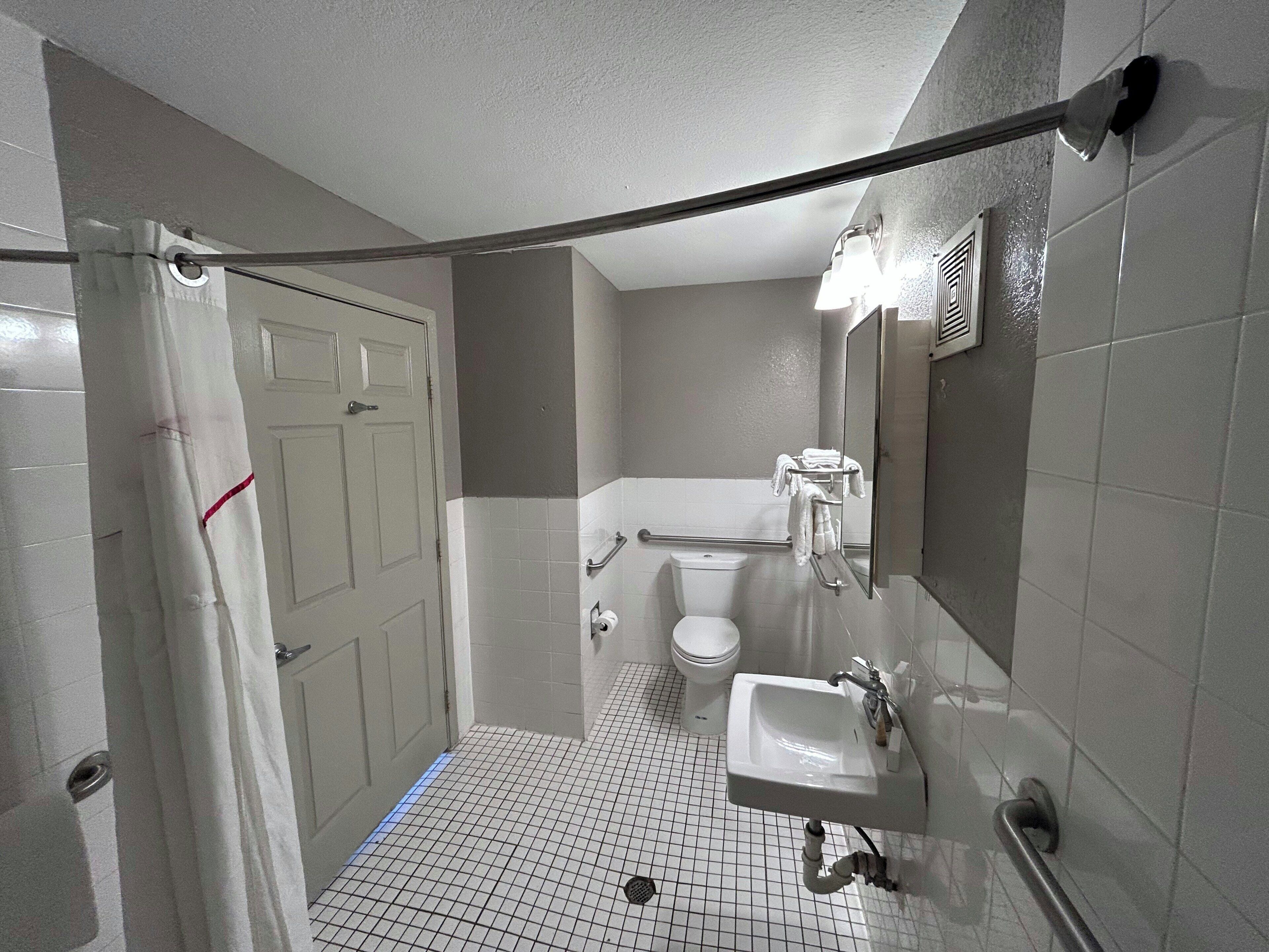 A small, compact bathroom with a toilet, sink, and mirror.