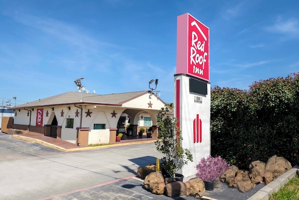 A Red Roof Inn with a simple facade, a parking lot, and a clear blue sky. - Red Roof Inn Arlington - Entertainment District (Arlington)