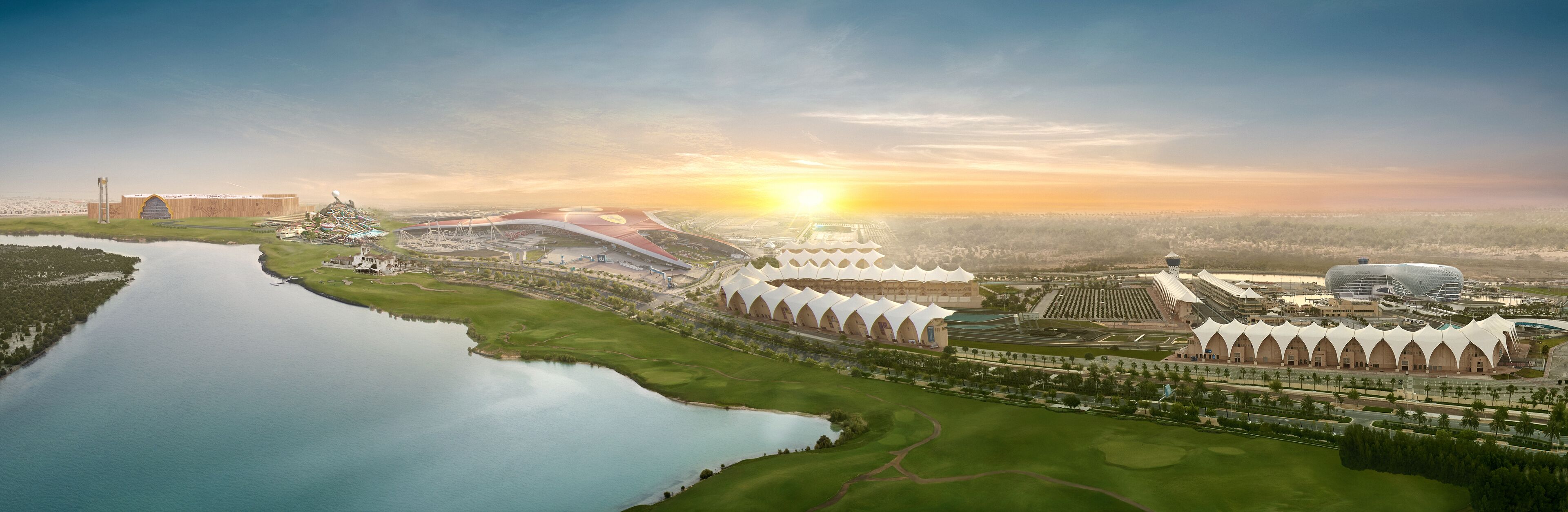 An aerial view of a modern architectural complex with a large stadium, a water body, and green spaces.