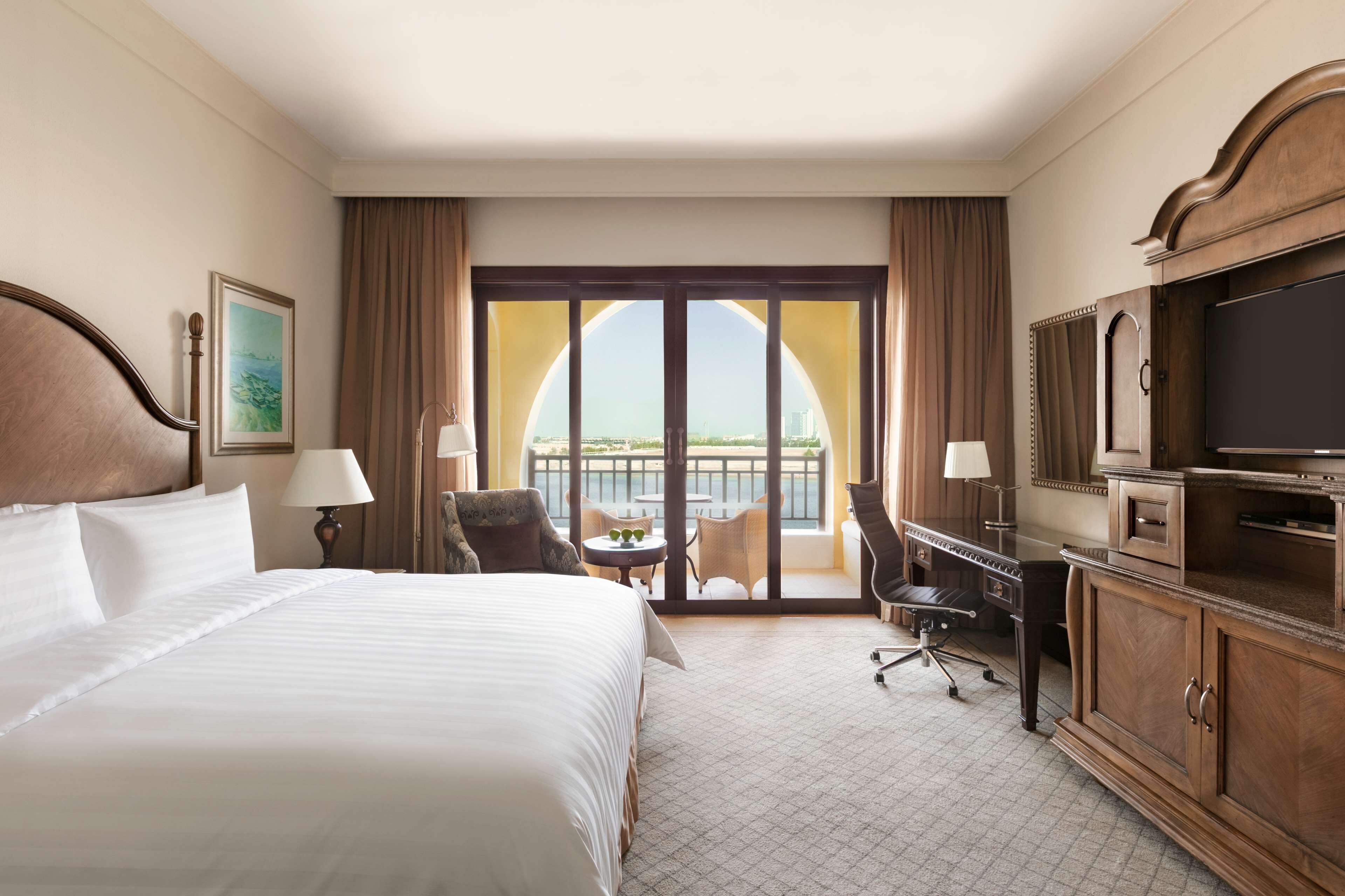 Une chambre d’hôtel avec un grand lit, un bureau, une télévision et un balcon avec vue.