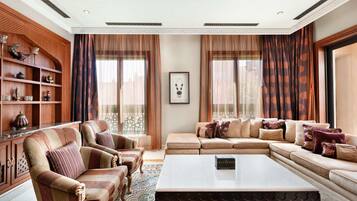 A spacious living room with a large sofa set, a coffee table, and a wooden cabinet with decorative items.