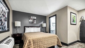 Een hotelkamer met een bed, twee nachtkastjes, een verwarming, een raam met jaloezieën en een foto in een lijst aan de muur.