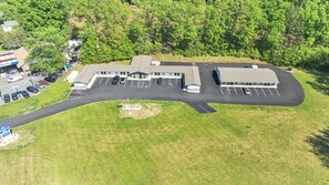 An aerial view of a commercial building with a parking lot, adjacent to a wooded area. - Best Way Inn (Rockfall)