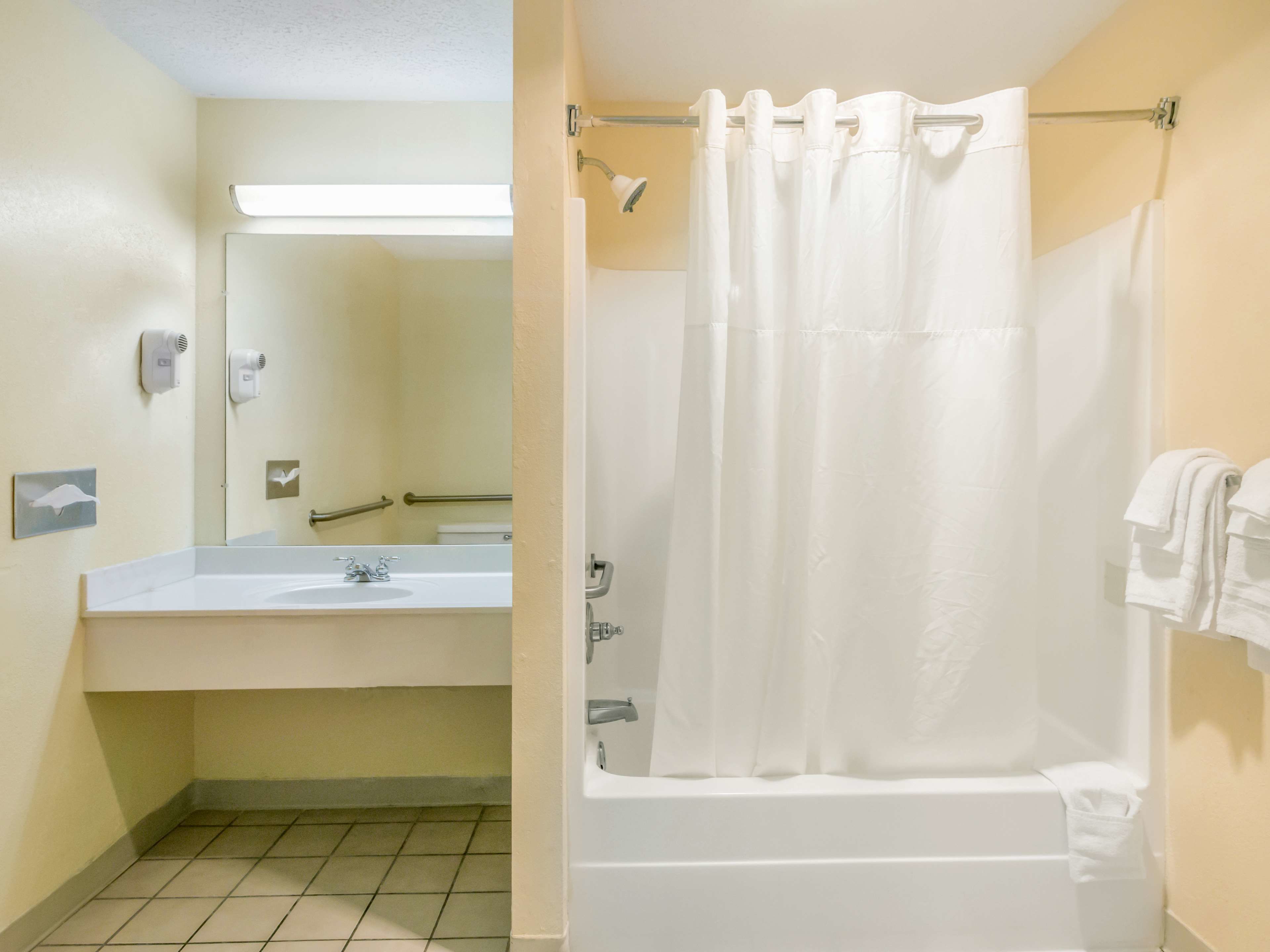 Un baño con lavamanos, espejo y cortina de ducha.