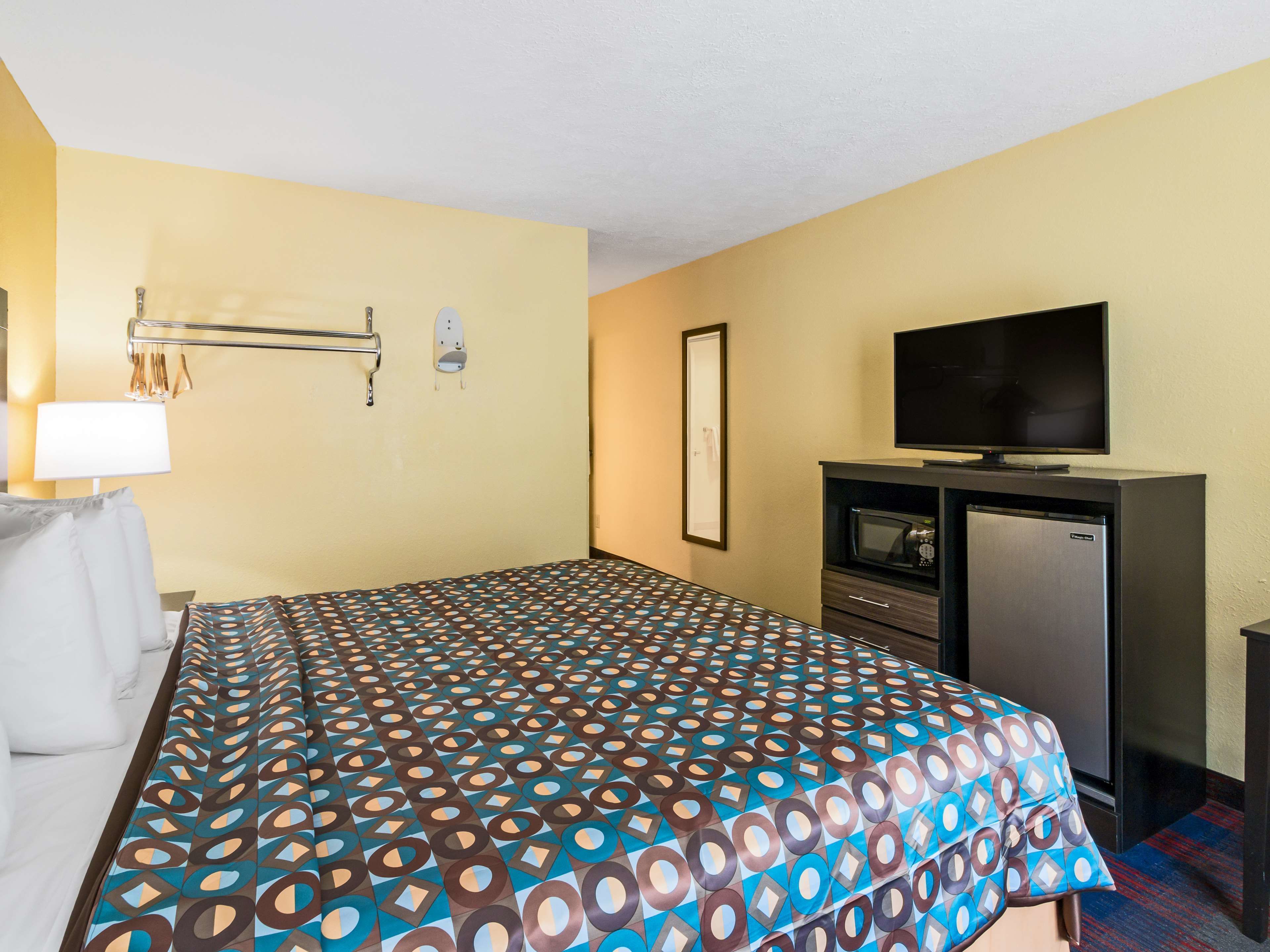A hotel room with a bed, a television, a microwave, and a desk.