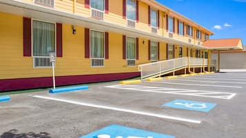 A yellow building with blue handicap parking spaces and a ramp leading to the entrance.