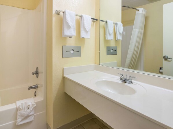 A bathroom with a white sink, a mirror, and a towel rack with multiple white towels.