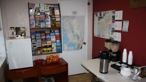 A kitchen with a refrigerator, a coffee maker, and a bulletin board with maps and notes. - Americas Best Value Inn Livermore (Livermore)