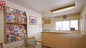 A reception area with a bulletin board filled with travel brochures, a clock, and a window with a view of the street. - Americas Best Value Inn Livermore (Livermore)