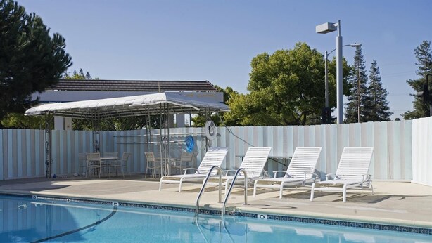 A swimming pool with lounge chairs and a covered seating area. - Americas Best Value Inn Livermore (Livermore)