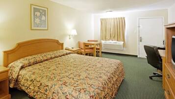A hotel room with a bed, a desk, a chair, a television, and a window with curtains.
