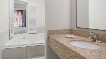 Un baño moderno con una bañera independiente, un lavabo con encimera de granito y un espejo grande.