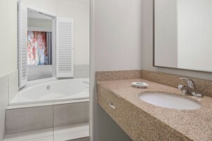 Un baño moderno con una bañera independiente, un lavabo con encimera de granito y un espejo grande.