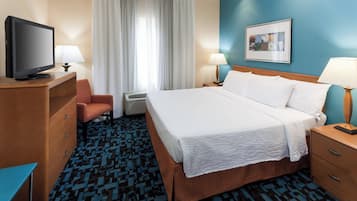 Habitació d'hotel amb un llit, televisió, escriptori, cadira i finestra amb cortines.