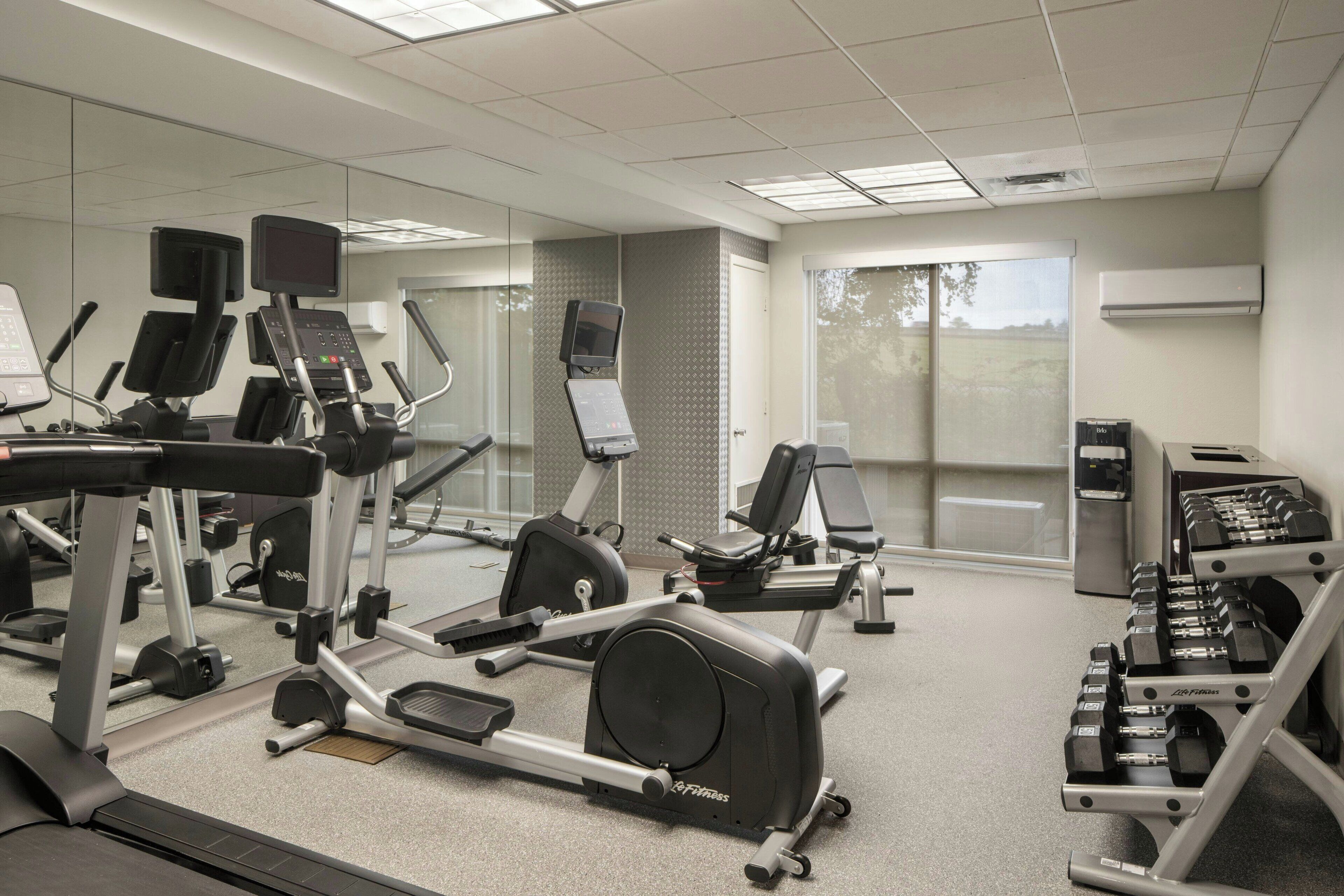 A gym with various exercise equipment including treadmills, elliptical machines, and weight benches.