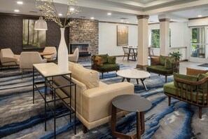 A spacious lobby with a stone fireplace, comfortable seating, and a large window offering a view of the outdoors. - Fairfield Inn & Suites Ruston (Ruston)
