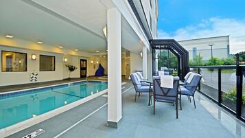 A poolside area with a pool, lounge chairs, and a covered seating area.