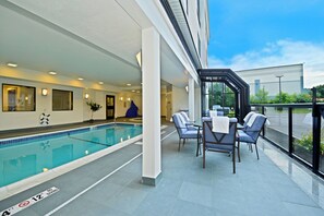 A poolside area with a pool, lounge chairs, and a covered seating area.