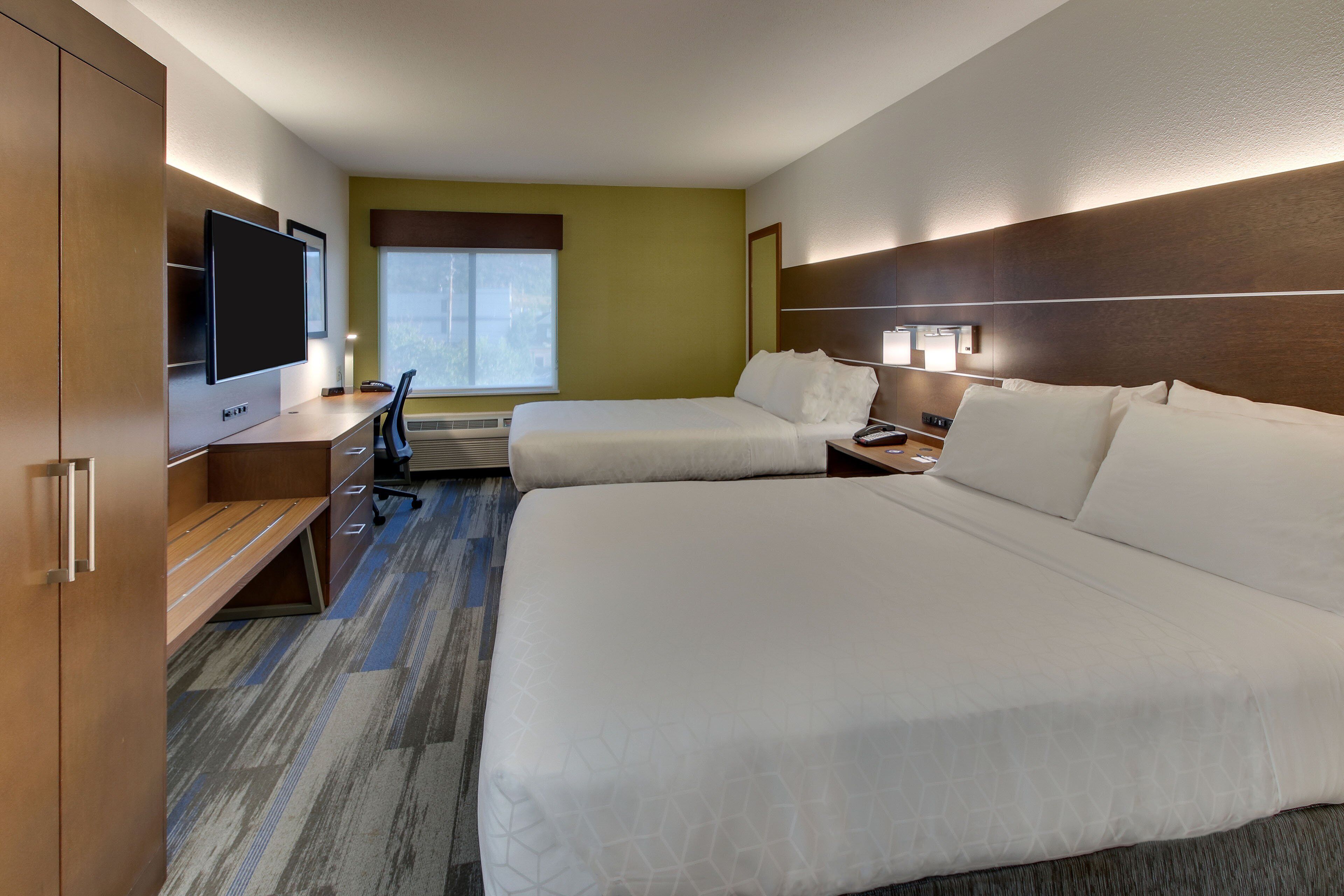 Habitación de hotel con dos camas, un escritorio, televisión y ventana.
