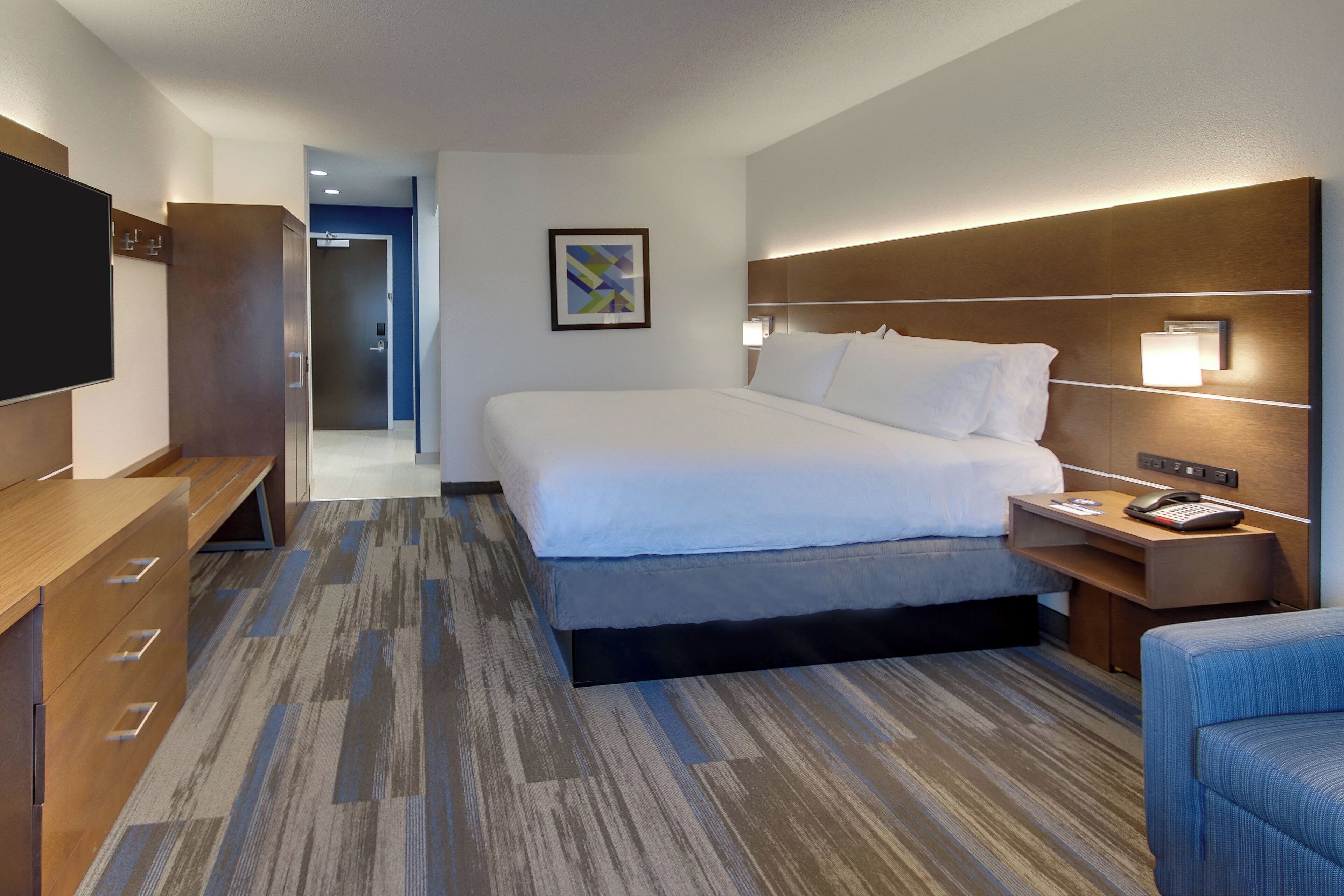Una camera d'albergo con un letto, un comodino, una scrivania e una televisione.