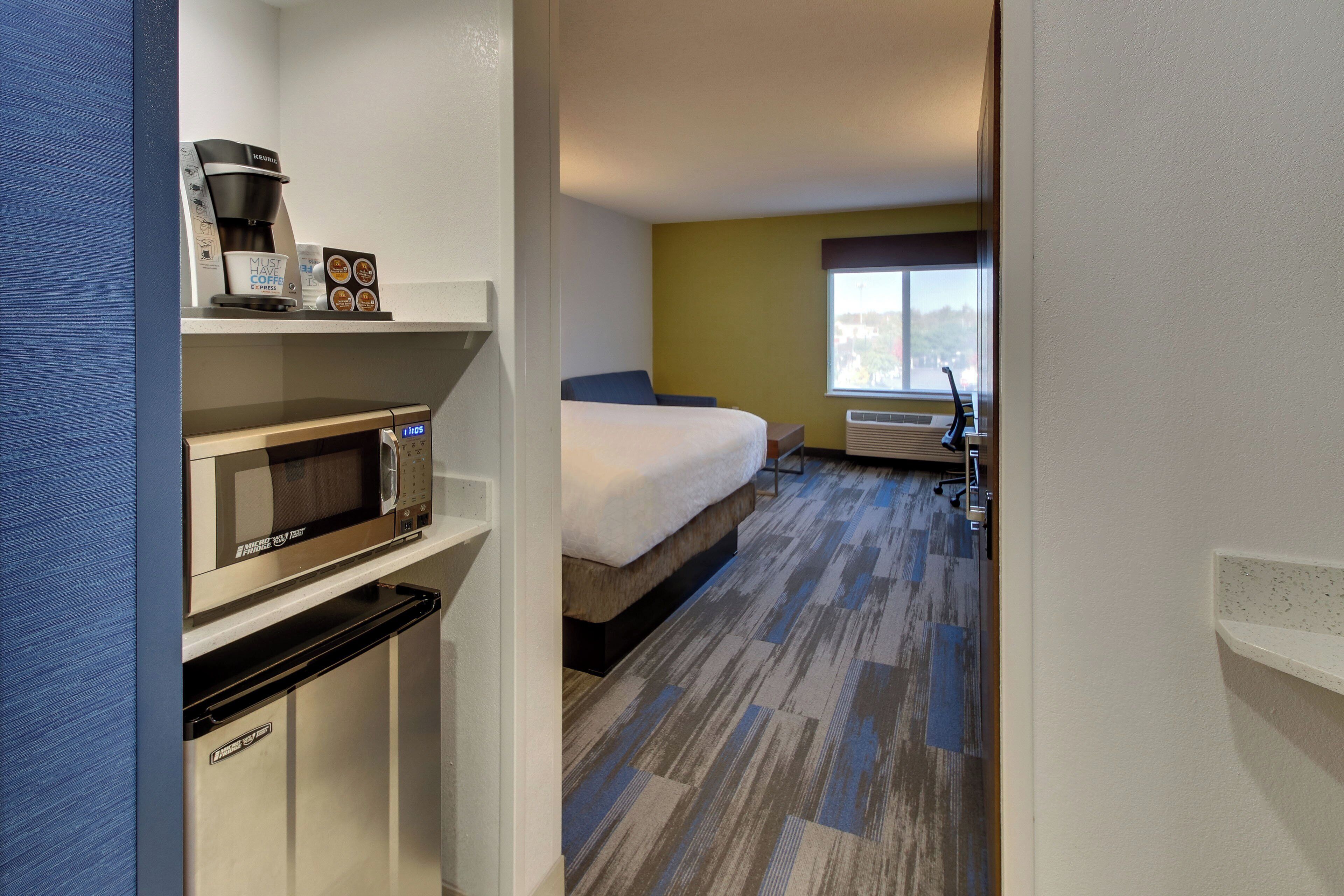 A hotel room with a bed, a microwave, a coffee maker, and a window with a view.