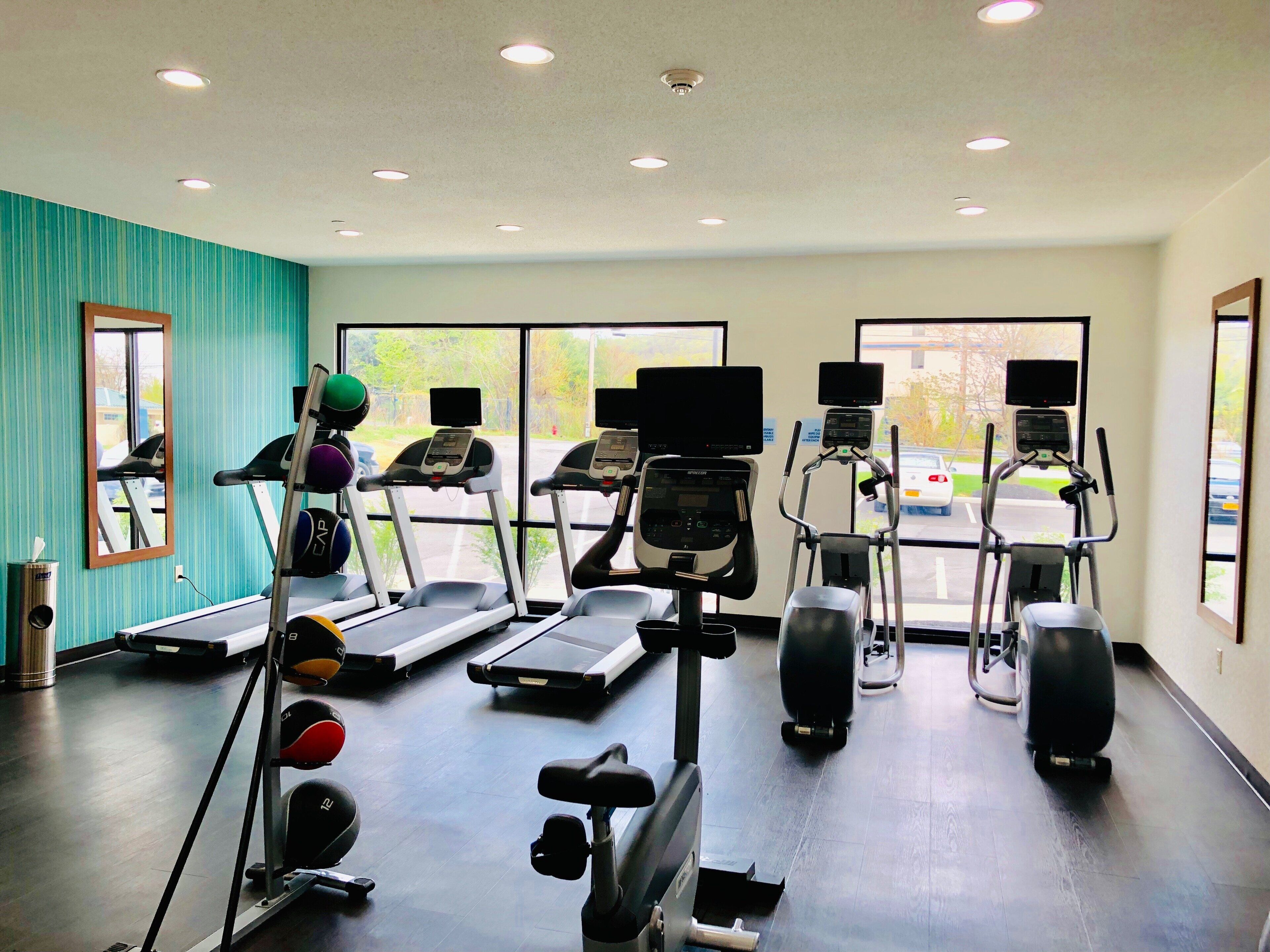 Un gimnasio con cintas de correr, elípticas y equipo de pesas.