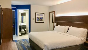A hotel room with a large bed, a bathroom with a sink and mirror, and a door leading to another room. - Holiday Inn Express Fishkill-Mid Hudson Valley by IHG (Fishkill)