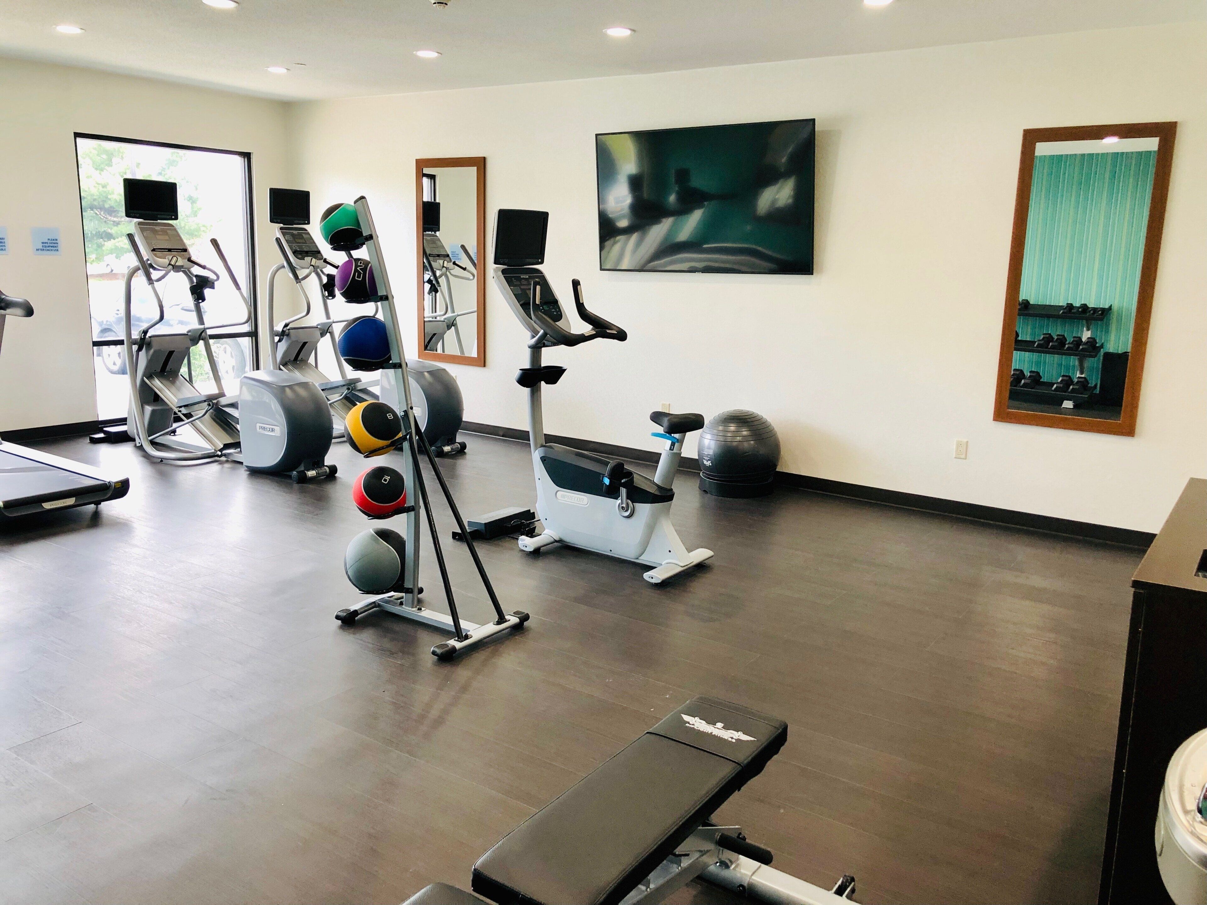 A gym with treadmills, elliptical machines, and a bench.