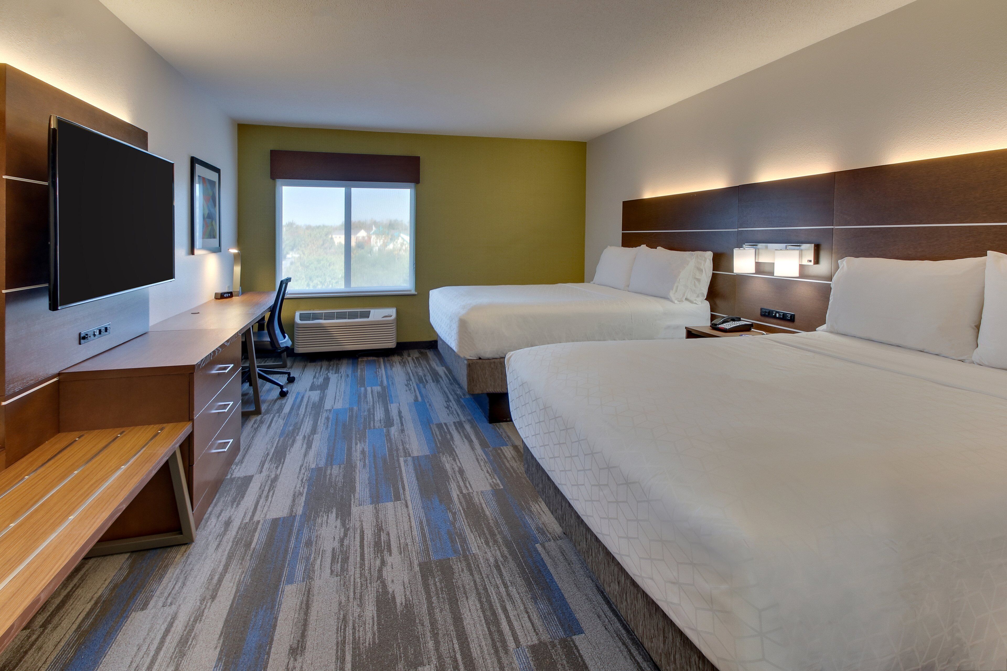 A hotel room with two beds, a desk, a flat-screen TV, and a window with a view.