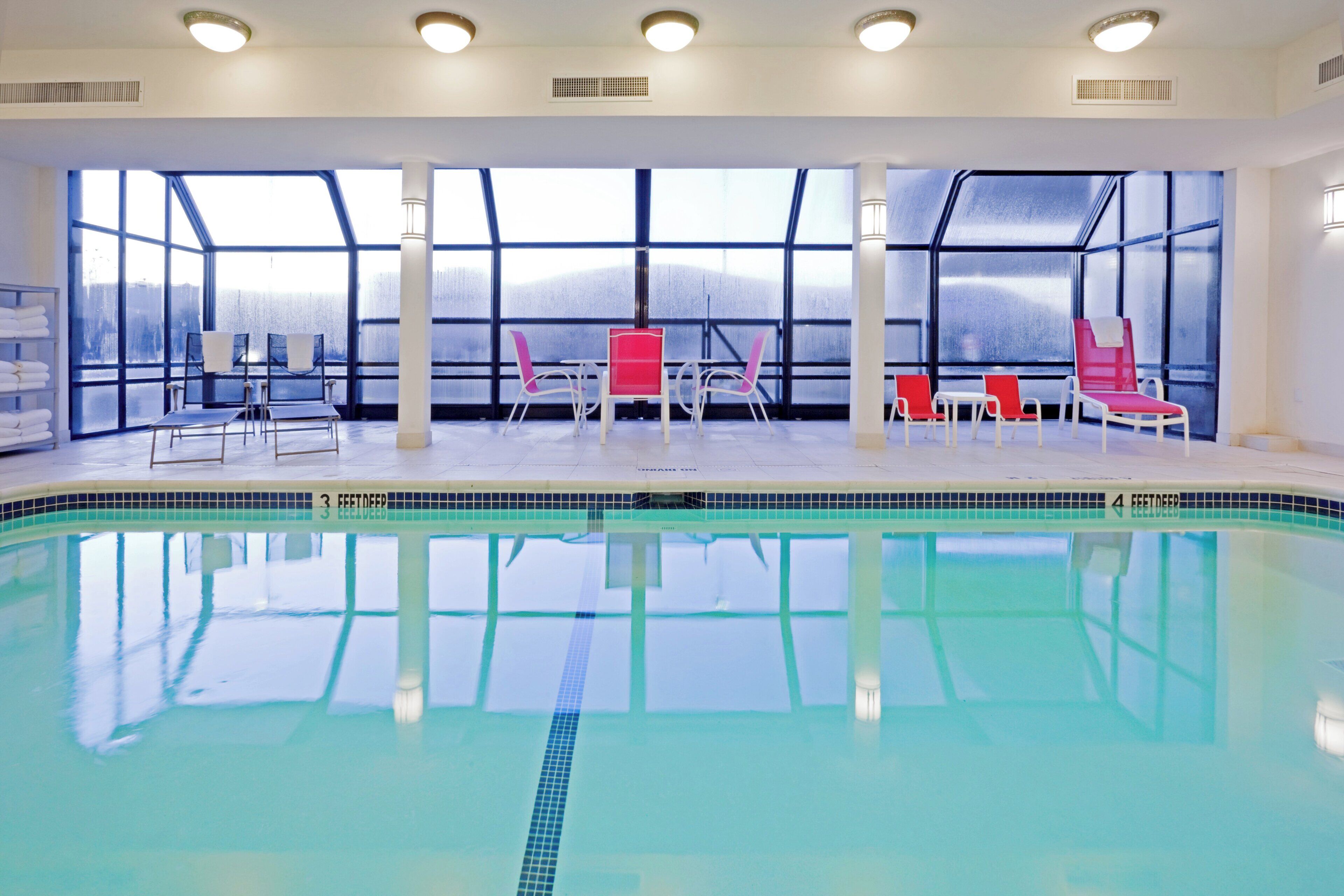 Una piscina interior con agua cristalina, rodeada de sillas y vistas a un paisaje nevado a través de amplias ventanas.