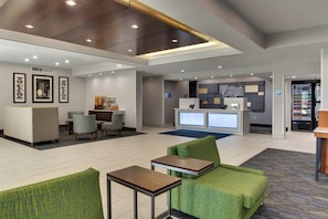 A hotel lobby with seating areas, a reception desk, and vending machines.