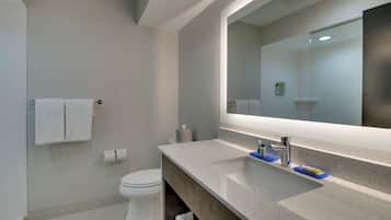 Une salle de bain moderne avec un grand miroir, des toilettes et un lavabo.