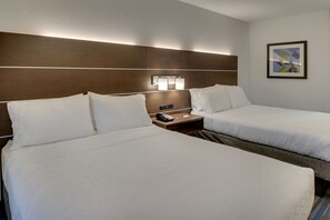 A hotel room with two beds, a nightstand with a phone, and a wall-mounted light fixture.