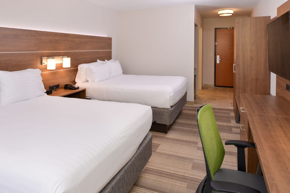 Ett hotellrum med två sängar, ett skrivbord och en stol.